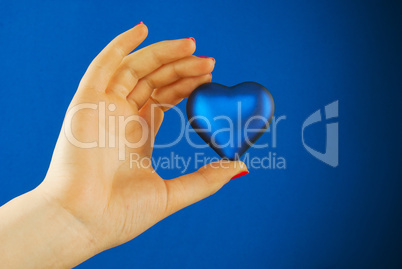 Hand holds a heart shaped gift against blue background