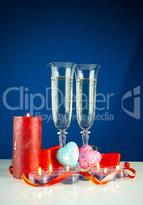 Two wineglasses and burning candles against blue background Two wineglasses and burning candles against blue background