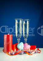 Two wineglasses and burning candles against blue background