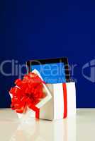 Tablet PC in a gift box against blue background