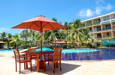 The table and chairs of outdoor restaurant near swimming pool at