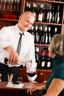 Wine bar waiter serving senior woman glass
