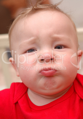 Closeup of unhappy caucasian boy in red t-shirt.