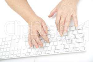 Hands of an old female typing on the keyboard, isolated on white, close-up.