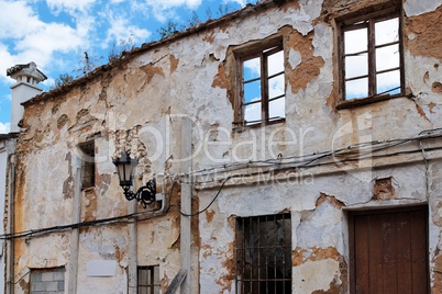 Facade of a very old ruined house with sky seen through empty windows