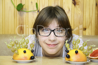 The cheerful girl and ridiculous hedgehogs from fruit on a table