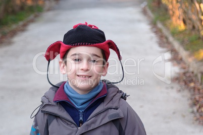 Cute little boy head in a funny hat outdoor in autumn