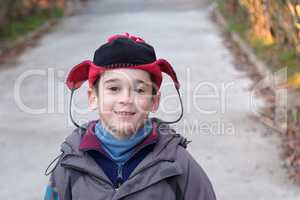 Cute little boy head in a funny hat outdoor in autumn