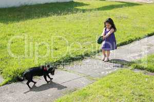 Little girl having trouble with her dog in the park