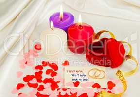 Two rings and a card with marriage proposal with three candles