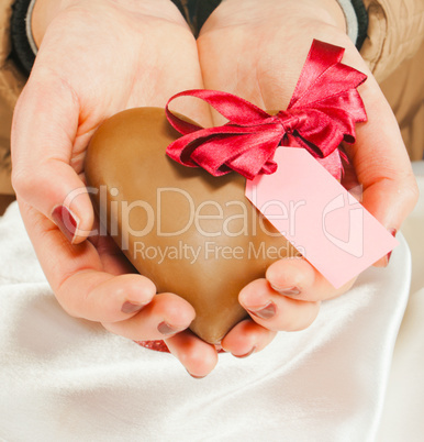 Hands holding a heart shaped chocolate candy