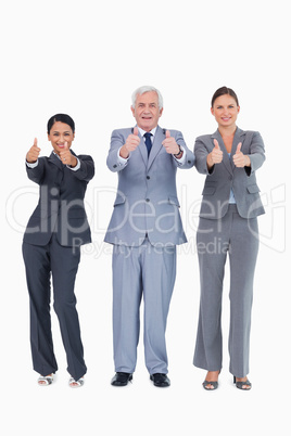 Three smiling businesspeople giving thumbs up