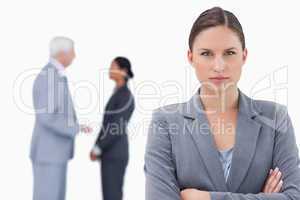 Businesswoman with arms folded and colleagues behind her