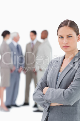 Saleswoman with folded arms and colleagues behind her