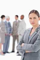 Saleswoman with folded arms and colleagues behind her