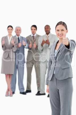 Saleswoman with thumb up and her team behind her