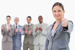 Businesswoman with thumb up and colleagues behind her