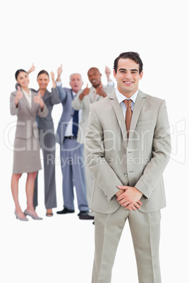Smiling businessman with cheering team behind him