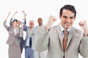 Smiling businessman with team behind him raising fists