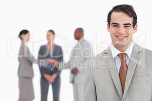 Smiling salesman with businesspeople behind him