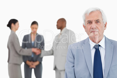 Mature businessman with trading partners behind him