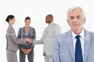 Mature businessman with trading partners behind him