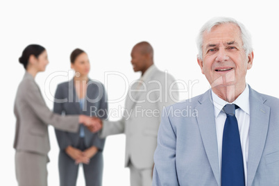 Mature salesman with trading partners behind him