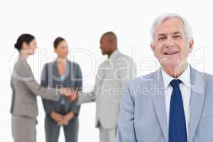 Mature salesman with trading partners behind him