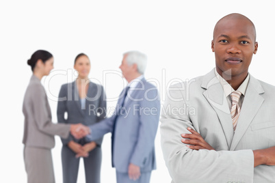 Businessman with arms folded and trading partners behind him