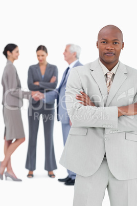 Businessman with folded arms and trading partners behind him