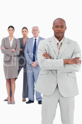 Businessman with folded arms and team behind him