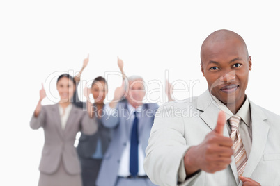 Businessman with cheering team behind him giving approval