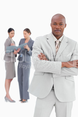 Businessman with crossed arms and colleagues behind him