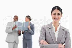 Smiling saleswoman with arms crossed and colleagues behind her