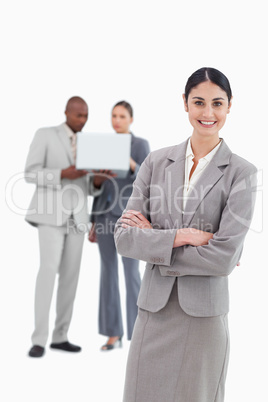 Smiling tradeswoman with folded arms and co-workers behind her