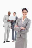 Smiling tradeswoman with folded arms and co-workers behind her