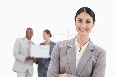 Smiling businesswoman with talking colleagues behind her