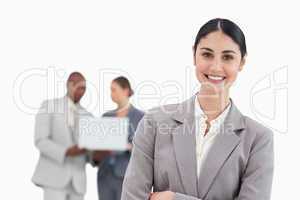 Smiling businesswoman with talking colleagues behind her