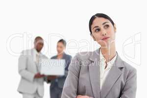 Daydreaming businesswoman with colleagues behind her