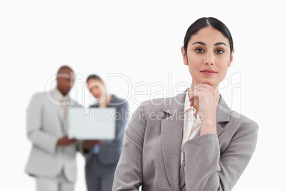 Thinking saleswoman with colleagues behind her