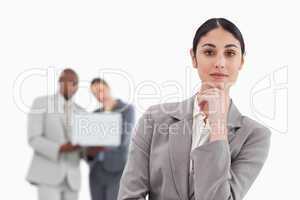 Thinking saleswoman with colleagues behind her