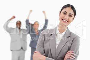Smiling businesswoman with cheering associates behind her