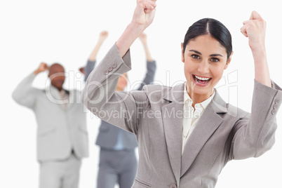 Triumphant businesswoman with cheering associates behind her