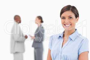 Smiling businesswoman with talking associates behind her