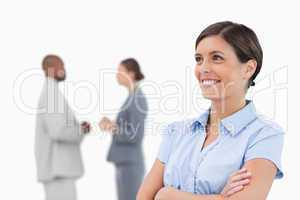 Smiling businesswoman with crossed arms and colleagues behind he