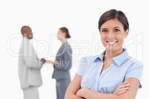 Smiling businesswoman with arms crossed and colleagues behind he