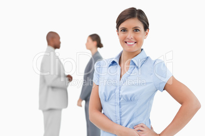 Smiling tradeswoman with talking associates behind her