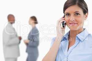 Tradeswoman with mobile phone and associates behind her