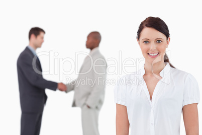 Smiling businesswoman with hand shaking trading partners behind