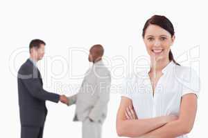 Businesswoman with arms folded and hand shaking trading partners